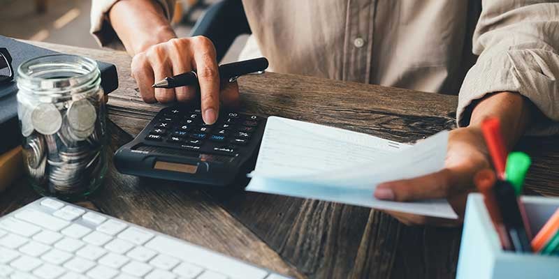 Man budgeting with calculator and coins on desk