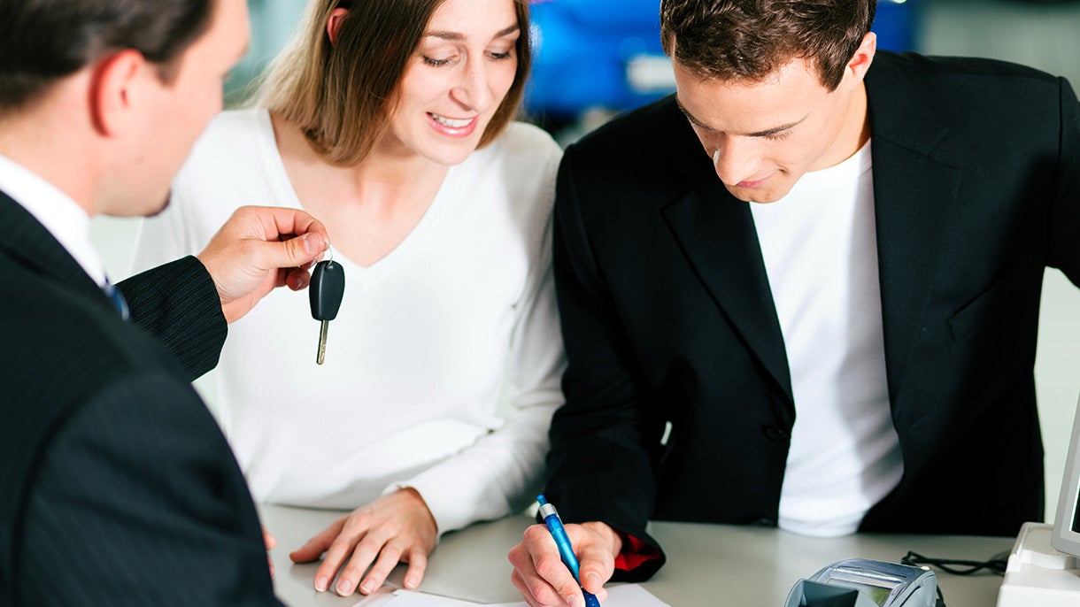 Smiling couple getting new car keys at showroom